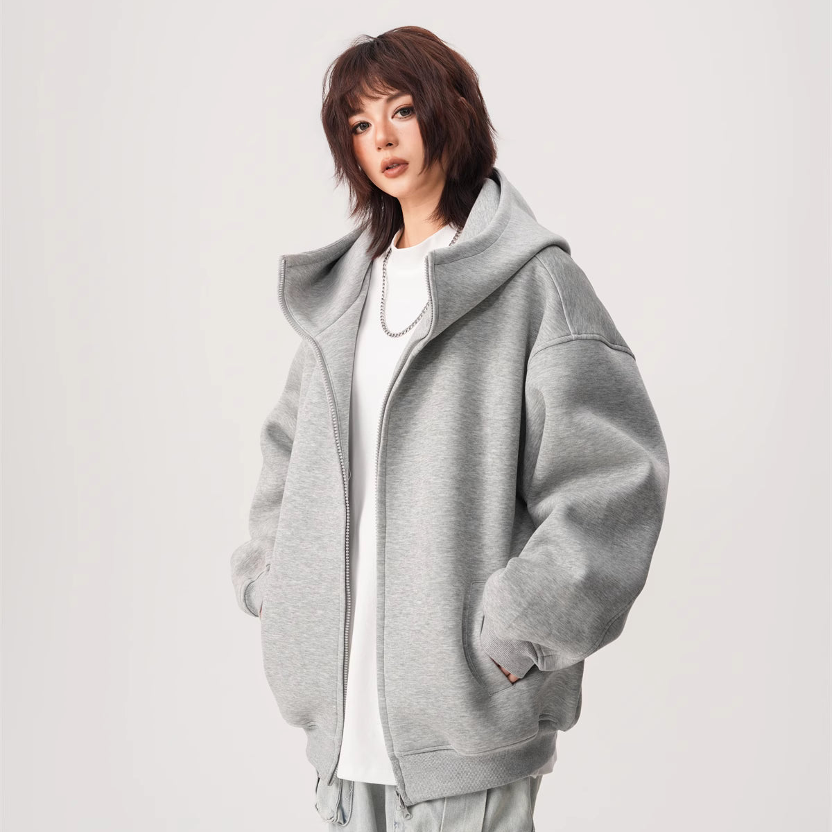 Person wearing a gray oversized jacket on a white background